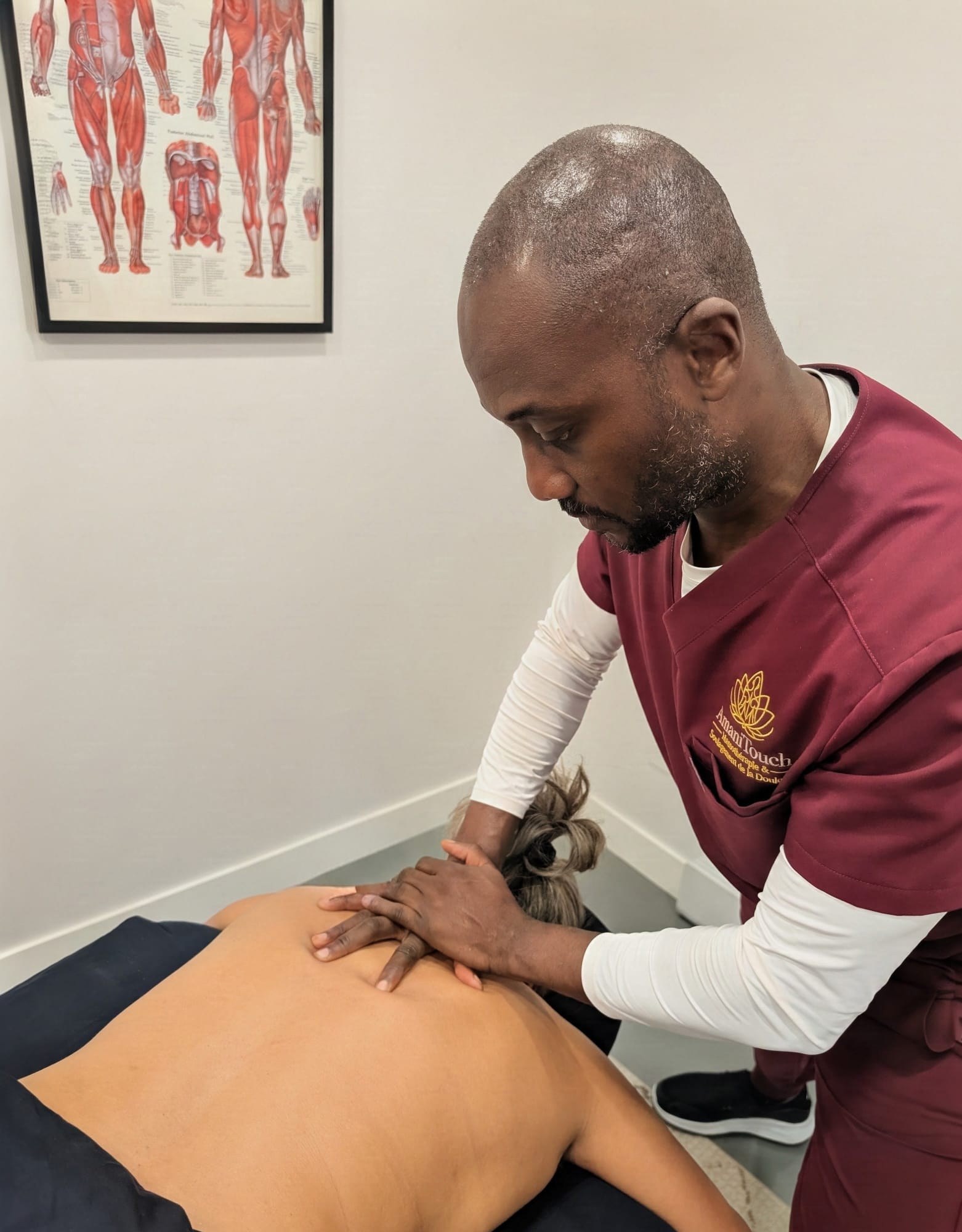 AmaniTouch massage therapist performing therapeutic deep tissue massage on a client's upper back.
